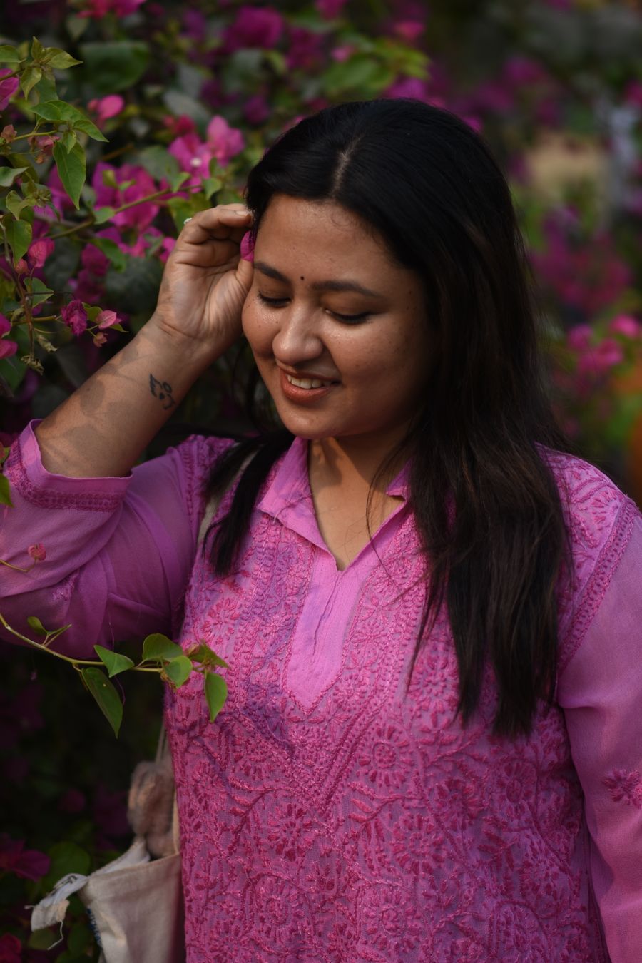 Woman in a rose pink chikankari kurti beside bougainvillea flowers